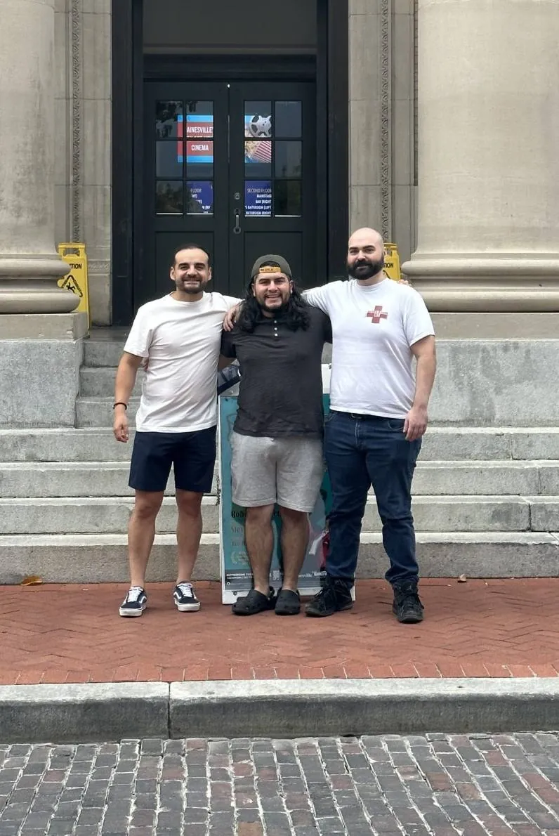 Three Progresíve team members outside a campus building